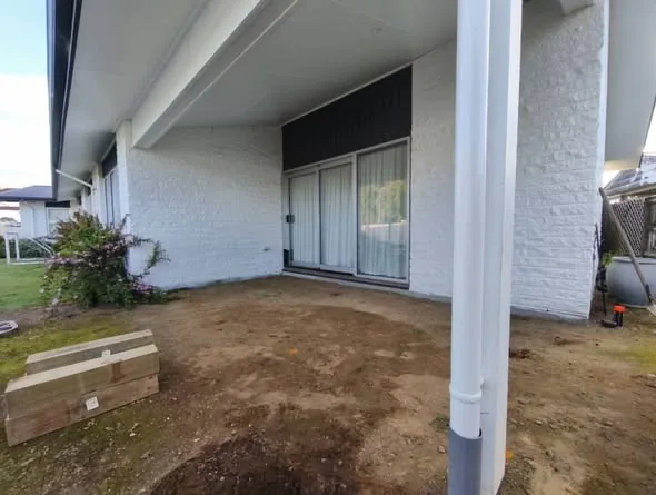 Bare yard and brick wall before the deck